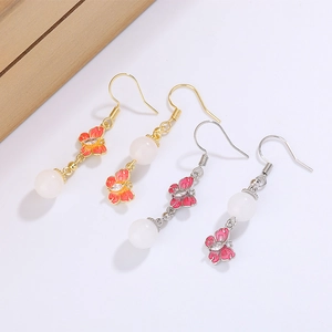Détail de boucles d'oreilles papillon vintage avec émail coloré et perles blanches