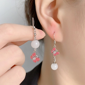 Détail de boucles d'oreilles papillon vintage avec émail rose et perle blanche