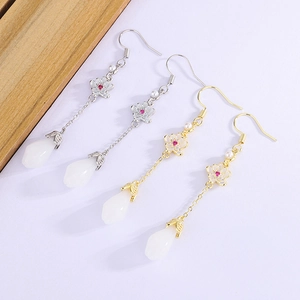 Detail of elegant magnolia tassel earrings with white jade-like teardrops and floral motifs