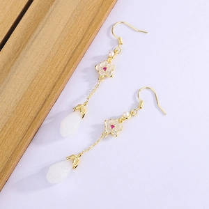 Close-up of vintage long tassel earrings with white magnolia jade and gold floral accents