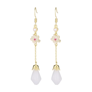 Close-up of vintage flower earrings with white petals, pink crystal and long gold tassels
