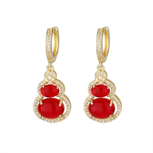 Detailed view of gold gourd earrings with red stones and zircon accents in white background