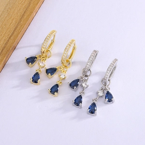 Close-up of gold and silver teardrop earrings with blue crystals and white cubic zirconia