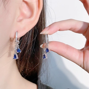 Detail of silver drop earrings with pear-cut blue sapphire zircons and crystal accents