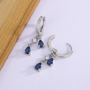 Detailed view of silver drop earrings featuring layered pear-cut blue sapphires and pavé diamonds