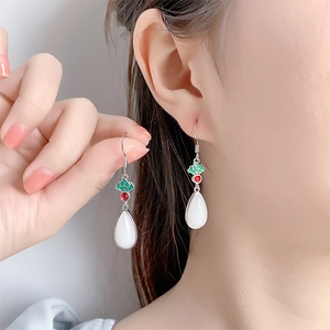 Detail of enamel cloud tassels and teardrop faux jade earrings on model ear