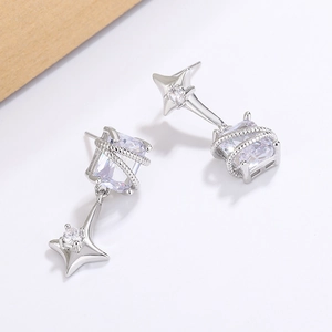 Détail de boucles d'oreilles asymétriques argentées avec zircon et pendentif étoile