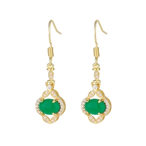 Close-up of gold drop earrings with emerald green stones and white crystal halo