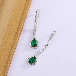 Close-up of pear-shaped emerald zircon drop earrings with micro-pave diamond accents