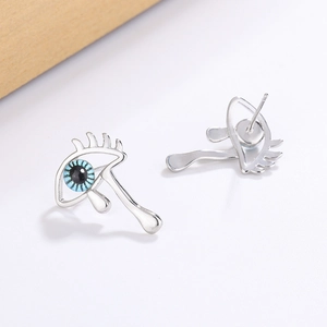 Silver evil eye stud earrings with blue pupil and hanging teardrop on white background