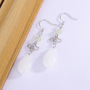 Macro shot of silver filigree auspicious cloud and white teardrop stone earring detail