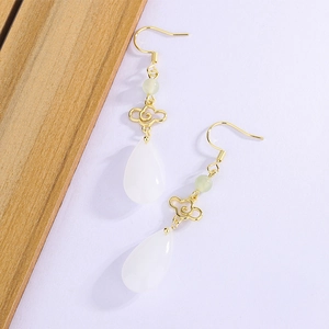 Detail of gold auspicious cloud earrings with white teardrop chalcedony in retro style