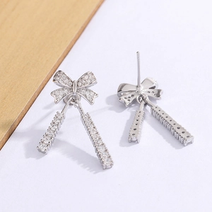 Macro detail of silver bow earrings with sparkling cubic zirconia and long tassels
