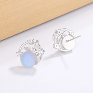 Close-up of fish tail stud earrings with blue opal stones and sparkling zircon details