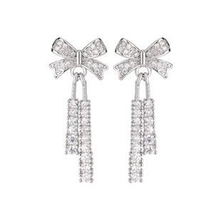 Detailed view of silver bow earrings with micro-pave cubic zirconia and hanging tassels