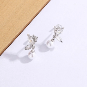 Détail macro de boucles d'oreilles perles papillon avec zircons et fini argent