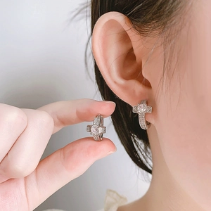 Détail des boucles d'oreilles croix en argent avec pavé de zircons sur l'oreille