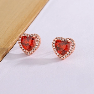 Macro shot of heart-shaped red gemstone studs with white zircon halo in rose gold