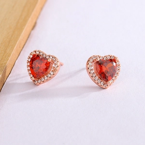 Macro shot of rose gold heart stud earrings with red crystal and white zircon stones