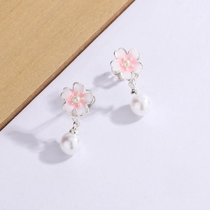 Pink cherry blossom earrings with round white pearls on a natural wood and white background