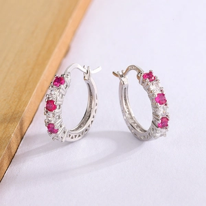Detailed view of silver hoop earrings featuring red and white zircon in a prong setting