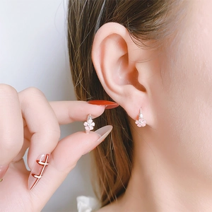 Détail des boucles d'oreilles fleurs de cerisier en émail rose portées par un mannequin
