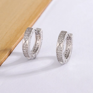 Close-up of silver-tone hoop earrings with Roman numeral engraving and cubic zirconia