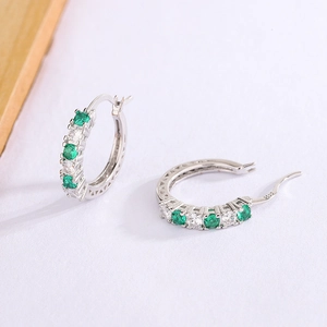 Detail of 925 sterling silver hoop earrings with alternating green and white zircons