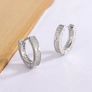 Detailed view of silver hoop earrings with Roman numerals and pavé set cubic zirconia