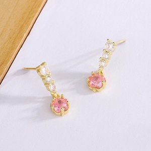 Détail de boucles d'oreilles fleur en zircon rose avec trois pierres blanches et fini doré