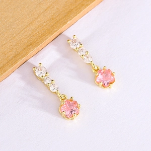 Détail de boucles d'oreilles étoile en zircon rose avec placage or et pierres blanches