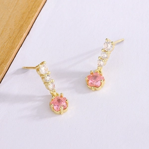 Boucles d'oreilles fleur en or avec zircon rose en étoile et cristaux sur fond minimaliste