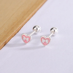 Detail of S925 sterling silver heart earrings with pink enamel and a silver bow accent