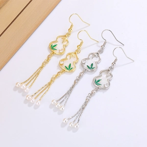 Detail of Chinese style gourd earrings with bamboo leaves and pearl tassels in gold and silver