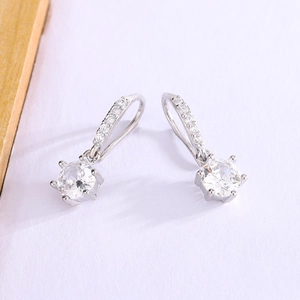 Elegant six-prong moissanite silver drop earrings with pavé set accents on textured background