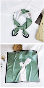 Close-up of green silk scarf featuring white rabbit print and contrast border detail
