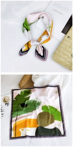 Close-up of pink silk scarf with tropical green leaves and striped edge detail