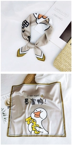 Detailed view of beige silk square scarf featuring cartoon duck and rich gold pattern
