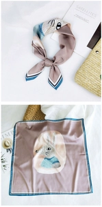 Detail of a pink silk square scarf with cartoon rabbit print and striped borders