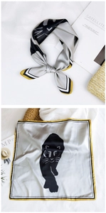 Detail of silk square scarf featuring black cat print and elegant gold striped borders
