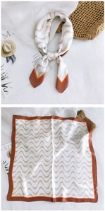 Detail of a square silk scarf featuring brown wave patterns and orange border design