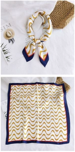 Detail of square silk scarf showing yellow wave pattern and navy blue contrast edges