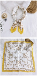 Detail of silk-feel scarf featuring golden anchor and chain patterns on white and yellow fabric