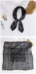 Close-up of black silk scarf featuring white celestial moon and sun astrological patterns