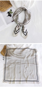 Detail of elegant beige polka dot silk scarf with black striped edges and smooth texture