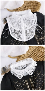 Détail d'un faux col en dentelle blanche avec motifs floraux ajourés et boutons à l'avant