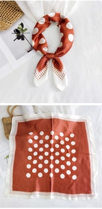 Detail view of brick red square silk scarf with white polka dot patterns and satin texture