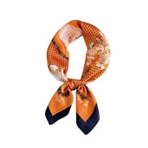 Orange satin square scarf with black polka dots and white floral patterns on white background