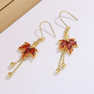 Macro detail of red maple leaf drop earrings with gold tassels and gemstone inlay