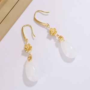 Détail macro de boucles d'oreilles lotus plaquées or 14K avec gouttes en jade blanc